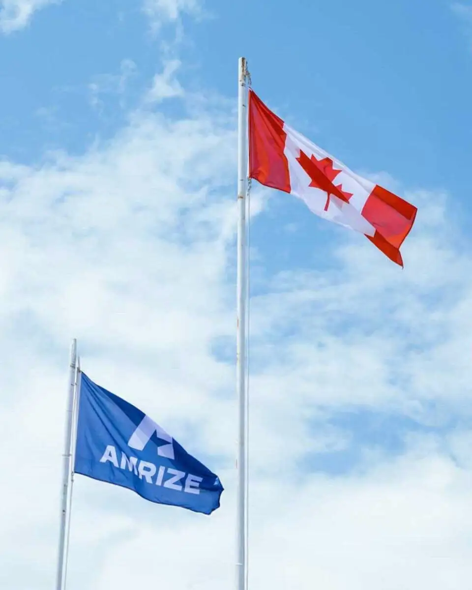 A Canadian flag flying above an Amrize flag